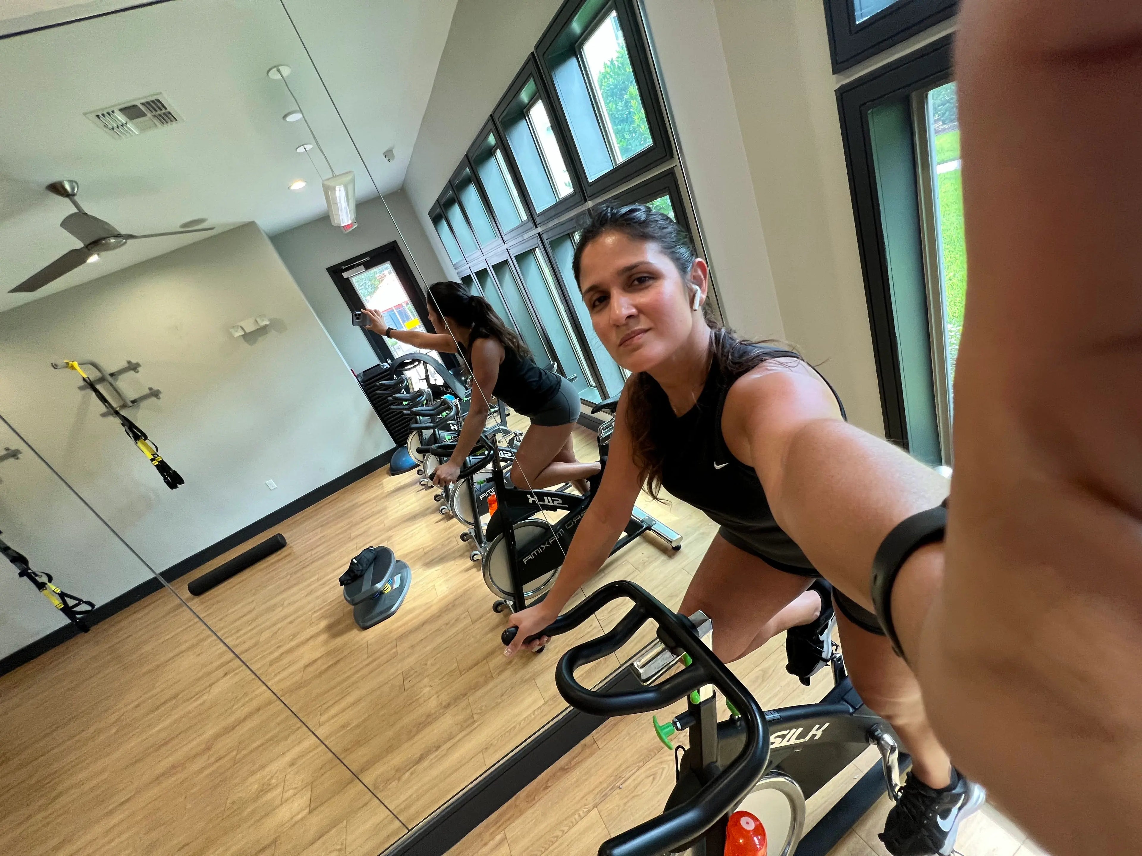 Mujer joven realizando entrenamiento de ciclismo indoor en bicicleta estática en un estudio de fitness iluminado
